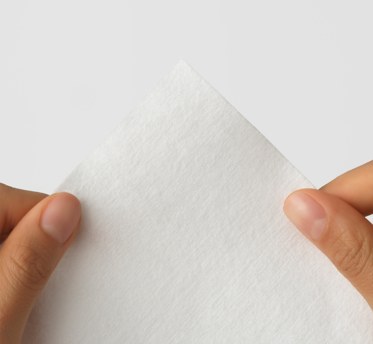 White cotton towelette La Delicate held between two hands on a light gray background