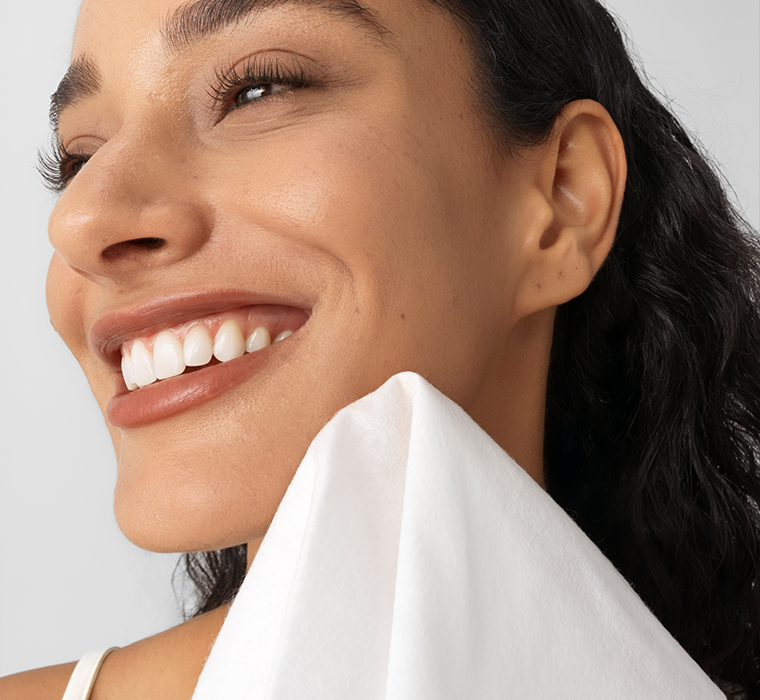 Close-up of a woman's face with a white cotton towelette with a light gray background